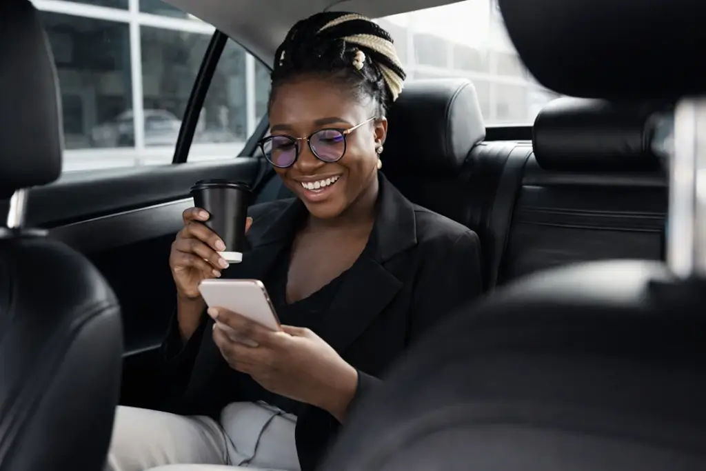 Smiling woman having coffee looking at smartphone in shuttle